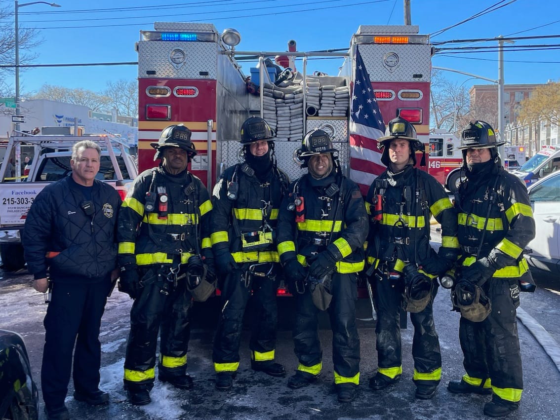 Squad 288 firefighters standing in front of apparatus with an American flag